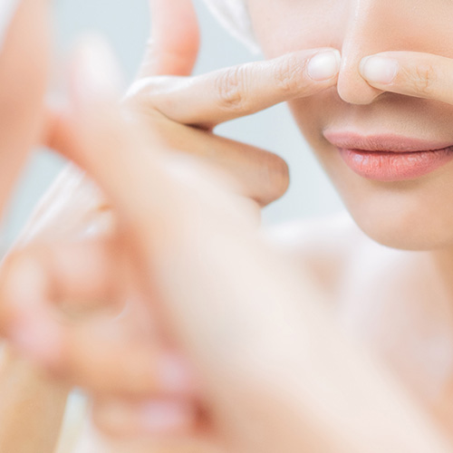 Close-up of person treating blackheads and whiteheads on face, skincare routine for clear skin